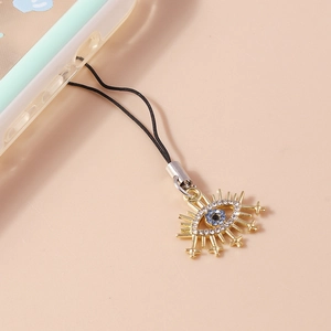 Detail of a bohemian evil eye phone charm with blue rhinestones and gold alloy frame