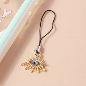 Detailed macro view of the golden Evil Eye phone charm featuring blue and white rhinestones