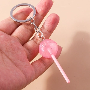 Detailed close-up of a pink glitter resin lollipop keychain held by a hand