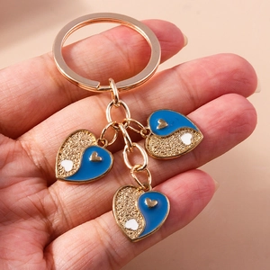 Porte-clés cœur doré avec pendentifs émaillés bleus style yin-yang et finition mate