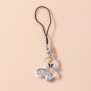 Detailed silver butterfly phone charm with sparkling rhinestones on a warm beige background