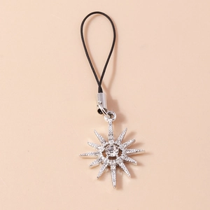 Detailed macro view of a silver sunburst charm with sparkling rhinestones and a black cord
