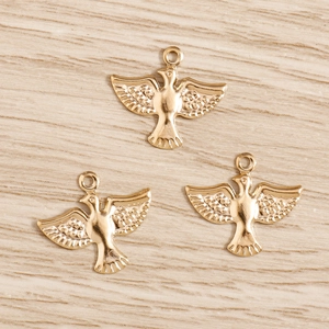 Trois breloques d'aigle dorées pour bijoux DIY sur un fond de bois naturel