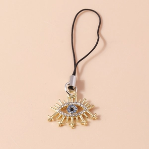 Detail view of Evil Eye phone charm with blue rhinestones and golden eyelash design