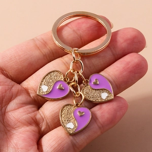 Détail de porte-clés en forme de cœur doré avec émail violet et paillettes yin-yang