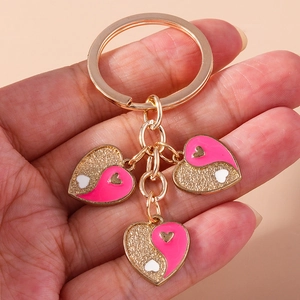 Gros plan d'un porte-clés doré avec des pendentifs en forme de cœur Yin Yang rose