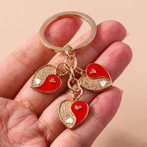 Détail de porte-clés cœur doré avec pendentifs émaillés rouge et or style yin-yang
