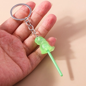 Close-up of a green translucent resin dinosaur lollipop keychain with silver metal ring