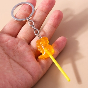 Close-up of an orange translucent dinosaur lollipop keychain with silver metal ring