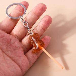 Detail of a brown resin dinosaur lollipop keychain with glitter flakes and silver ring
