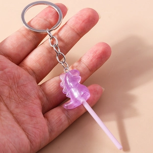 Detailed view of a purple resin dinosaur lollipop keychain with sparkling glitter finish