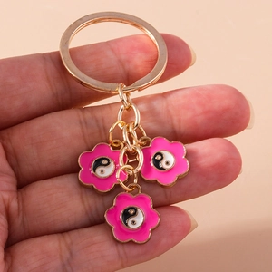Détail de pendentifs Tai Chi fleur rose plaqués or sur un anneau de porte-clés métal