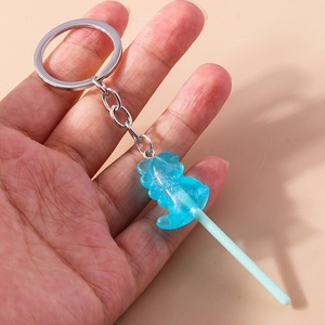 Detail of blue glittery dinosaur lollipop keychain with silver metal ring and chain