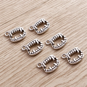 Macro detail of six retro silver vampire teeth alloy pendants for Halloween jewelry making