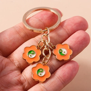 Détail d'un porte-clés doré avec pétales orange et breloques émaillées Yin et Yang