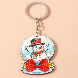 Détail d'un porte-clés globe de neige bonhomme de Noël avec nœud papillon rouge à pois