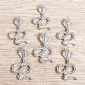 Vintage silver snake pendants for DIY necklaces and bracelets on wooden background