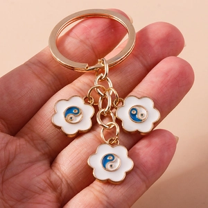 Détail de trois pendentifs Tai Chi floraux dorés sur un porte-clés tenu à la main