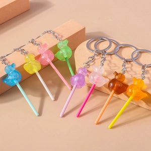 Detail showing eight colorful animal lollipop keychains on geometric blocks with glitter finish