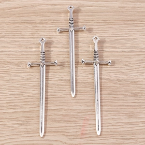 Primer plano de dijes de espada gótica plateada sobre madera para hacer joyería