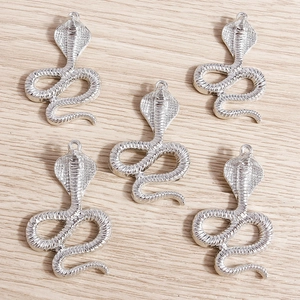 Set of five silver snake pendants with detailed scale textures on light wood background