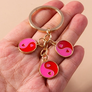 Détail du porte-clés en métal doré avec pendentifs en émail yin-yang et cœur