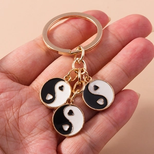 Détail de trois pendentifs Tai Chi Yin Yang en forme de cœur sur un porte-clés doré