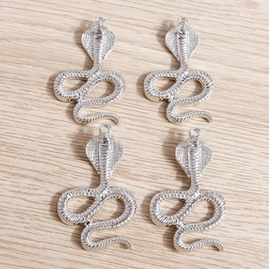 Detailed macro view of four silver cobra pendants featuring intricate snake scale textures