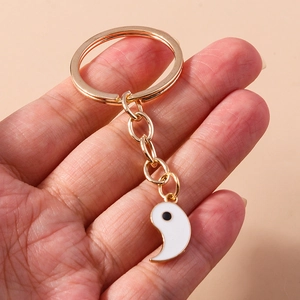 Gros plan d'un porte-clés doré avec pendentif yin-yang blanc en forme de goutte