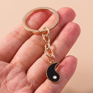 Gros plan d'un porte-clés Tai Chi Yin Yang doré avec finition en émail noir brillant