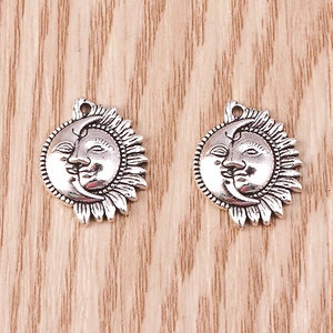 Macro detail of antique silver sun and moon charms with retro engraved faces on wood