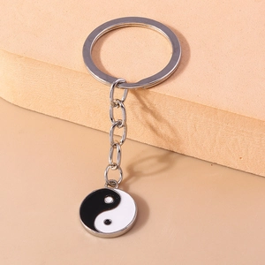 Gros plan d'un porte-clés en métal argenté avec un charme Tai Chi Yin Yang en émail bicolore
