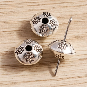 Detalle macro de cuentas espaciadoras de plata antigua con motivos florales retro