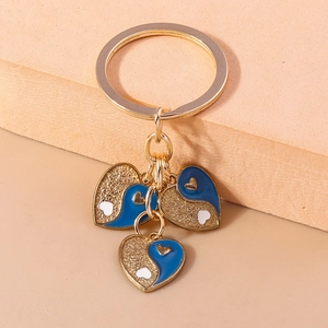 Gros plan de porte-clés triple cœur doré avec motifs yin-yang bleu et blanc et paillettes