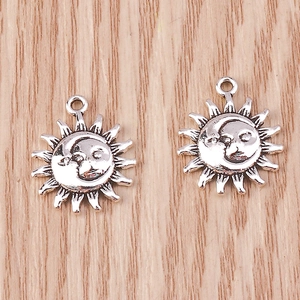 Detailed macro of vintage silver sun and moon face embossed pendants with ring hooks