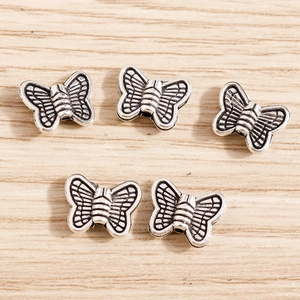 Retro-Silber-Schmetterlingsanhänger für DIY-Schmuckherstellung auf Holzgrund