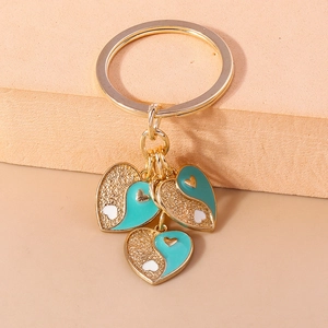 Gros plan de trois pendentifs cœur avec émail bleu canard et paillettes dorées sur porte-clés