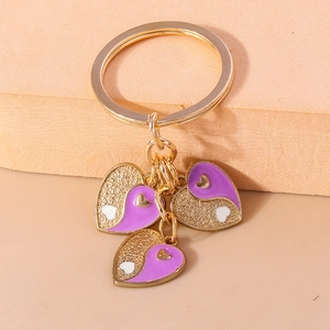 Détail de trois pendentifs en cœur avec émail violet et finitions pailletées dorées