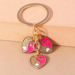 Détail macro de porte-clés Yin Yang en forme de cœur avec émail rose et paillettes dorées