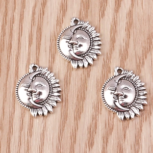 Close-up of three vintage silver celestial sun and moon pendants on a wood surface