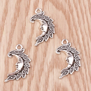 Detailed macro view of retro silver moon face pendants with embossed leaf edges