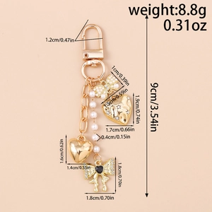 Detailed view of gold keychain with pearls and heart pendants showing 9cm length scale