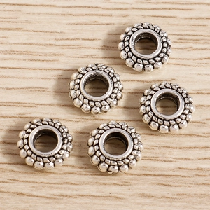 Primer plano de cuentas espaciadoras de plata retro con relieve sobre fondo de madera