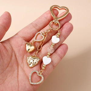 Golden heart keychain with pearls and rhinestones held in hand for bag decoration