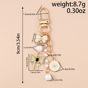 Detailed view of golden keychain with pearl bow and heart charms showing size and weight