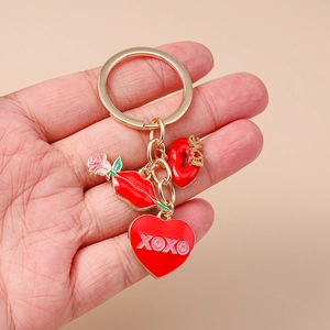 Détail d'un porte-clés doré avec cœur XOXO, lèvres Love et breloques de rose