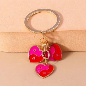 Détail de porte-clés cœur en émail rose et rouge avec finition en métal doré