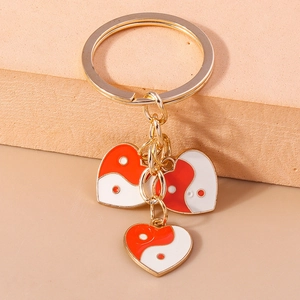 Vue macro de pendentifs cœur dorés avec détails en émail Tai Chi Yin Yang rouge et blanc