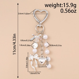 Detailed view of silver heart keychain with pearl bow and size measurements