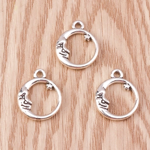 Close-up of antique silver crescent moon pendants with embossed faces for DIY jewelry